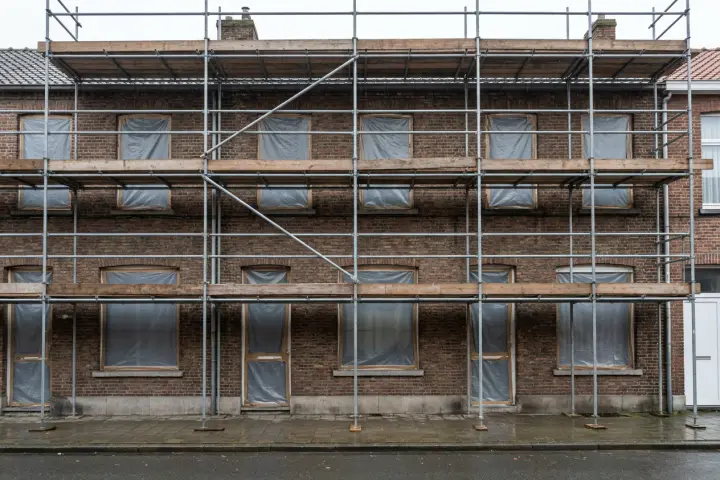 Stelling opgebouwd tegen de voorgevel van een woning, met beschermzeil over de ramen